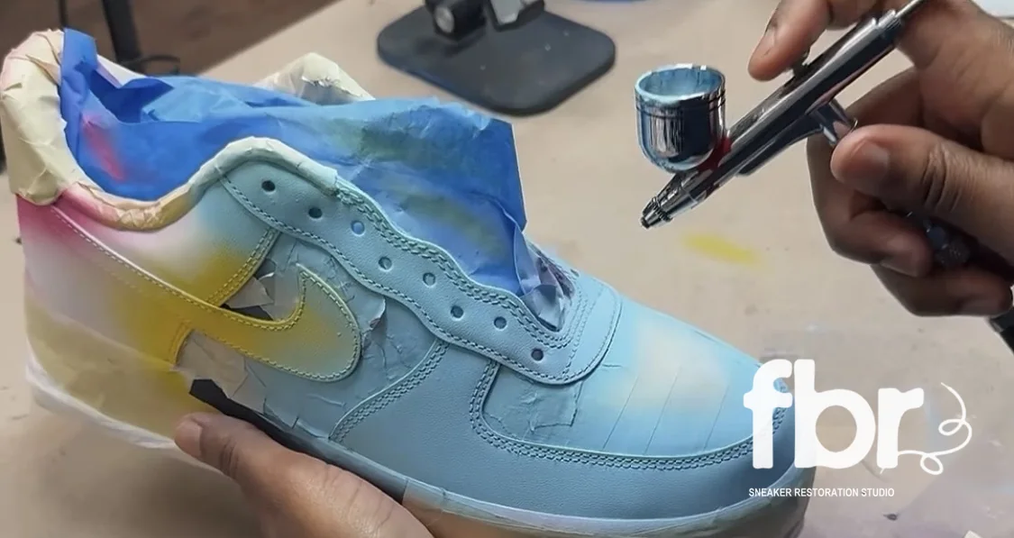 Reesey airbrushing a blue, pink and yellow fade onto a masked Air Force 1