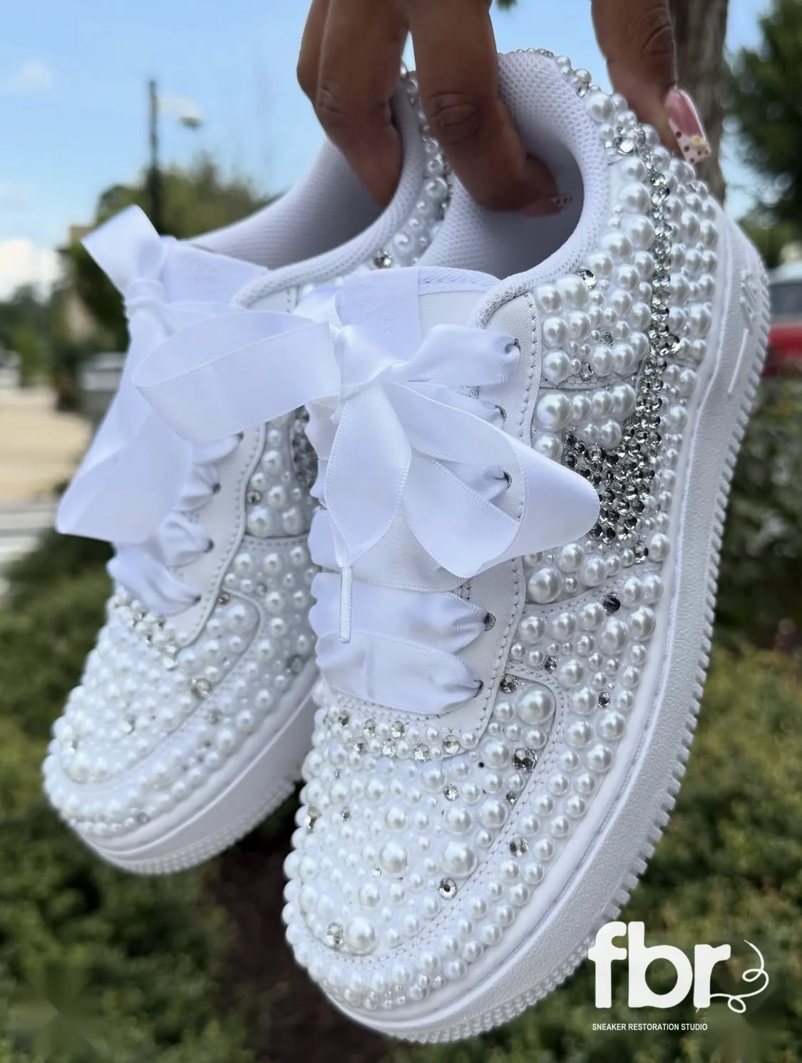 The same pearl and crystal Air Force 1s held up, both shoes together